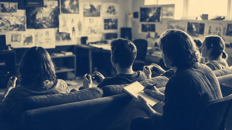 A game studio's open-plan office with rows of desks and dark monitors in a converted warehouse, plants and bicycles, late evening