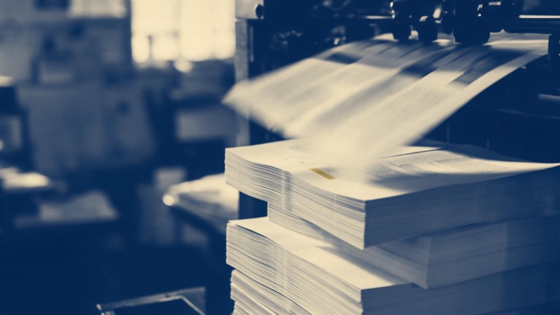 stacks of printed pages coming off a press, motion blur