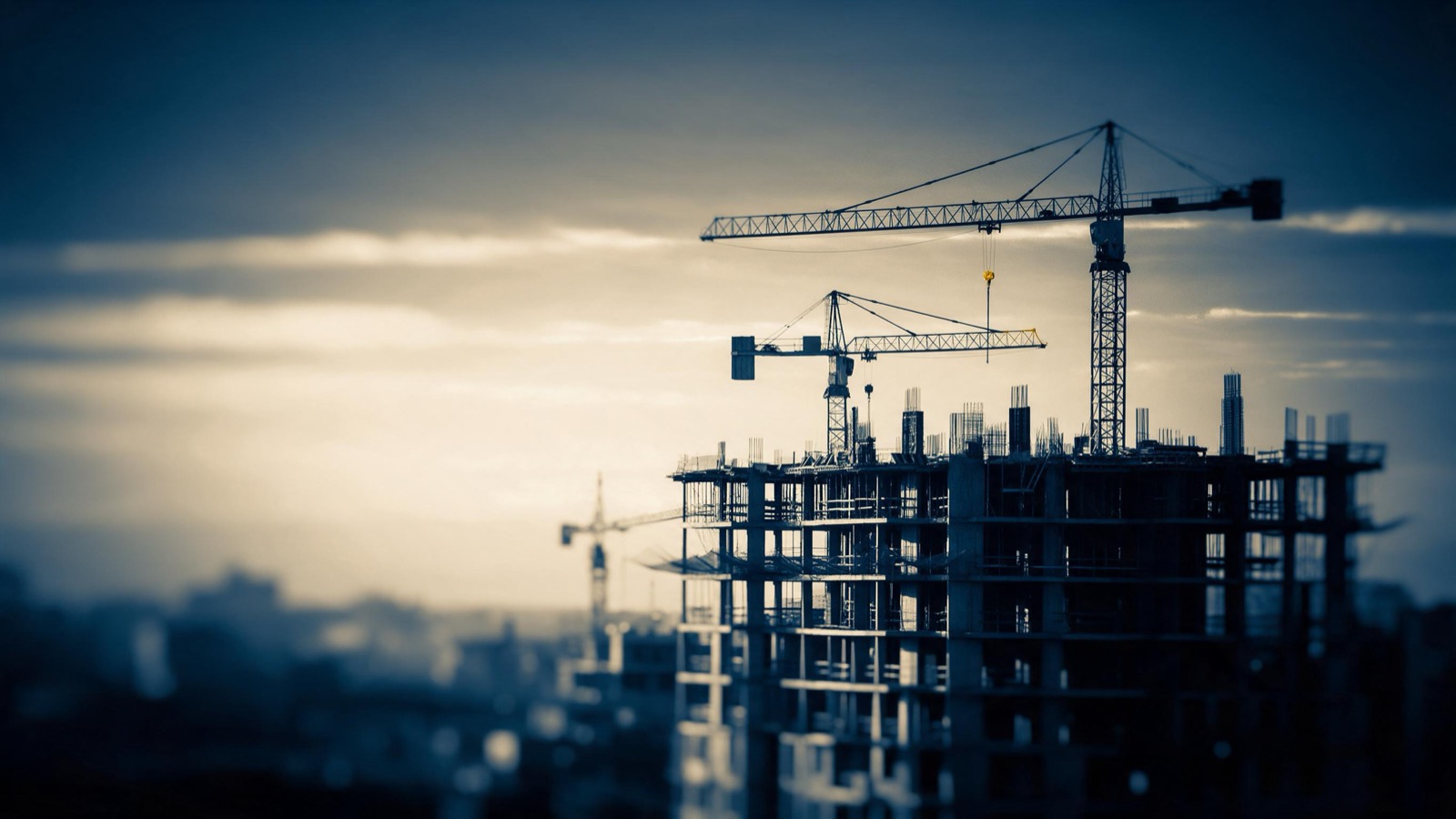 a city block under construction, cranes and concrete floors at sunrise