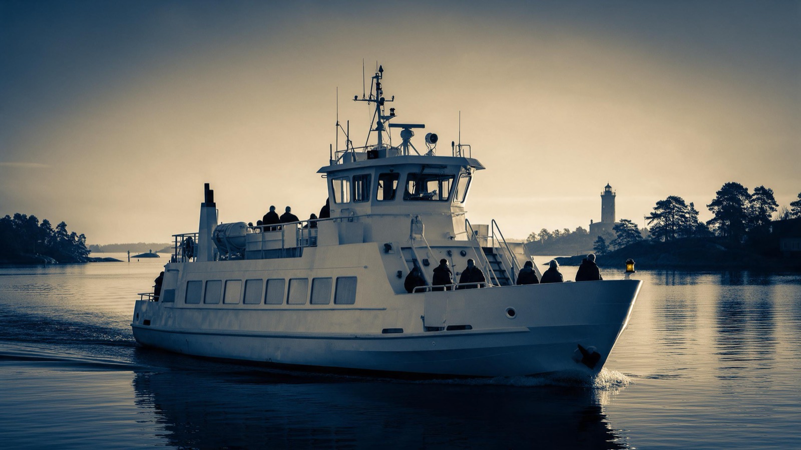 A white passenger ferry slowly entering a Baltic harbour at dawn, pink sky over still water, pine-clad islets and a lighthouse in the distance